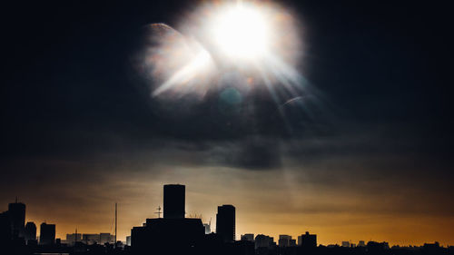 Digital composite image of sun over silhouette city against sky during sunset