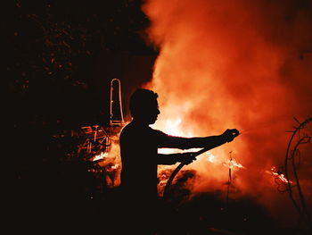 Silhouette man with fire crackers at night