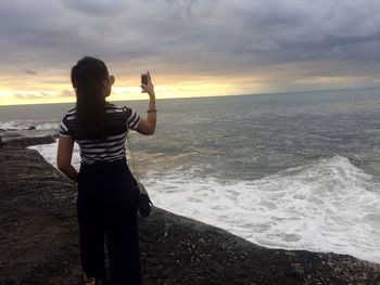 Full length of woman standing on beach against sky during sunset