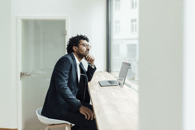 Side view of young man using mobile phone while standing in office