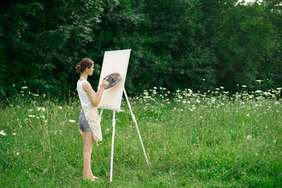 Woman holding umbrella while standing on field