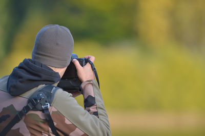 Man photographing through camera against tree