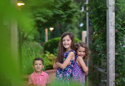 Portrait of happy siblings standing in park