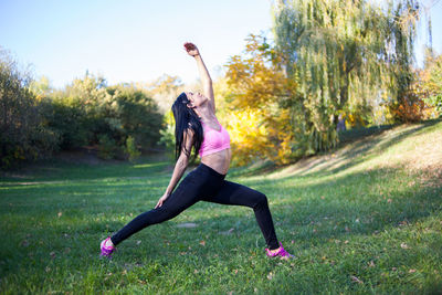 Young girl practices yoga in the park on the grass.