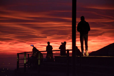 Silhouette people standing against orange sky