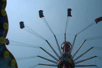 Low angle view of amusement park ride against clear blue sky