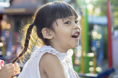 Cute smiling girl looking away while sitting outdoors