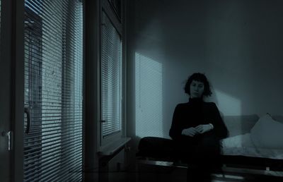 Portrait of young woman sitting by window