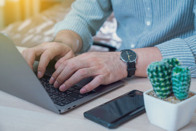 Midsection of man using laptop on table