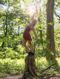 Woman standing by tree in forest