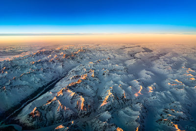 Aerial view of snowcapped landscape against sky during sunset