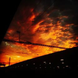 Low angle view of silhouette electricity pylon against dramatic sky