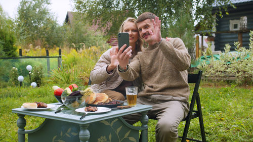 Couple talking on video call while having lunch outdoors