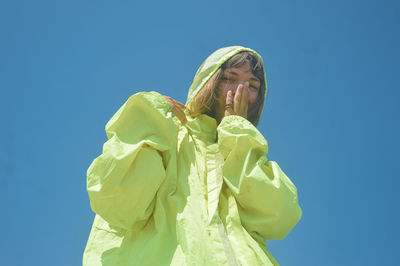 Low angle view of woman against clear blue sky