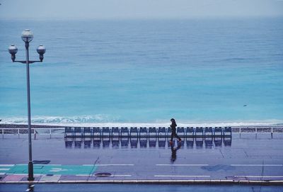 Woman walking on road against calm sea