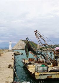 Fishing boats moored at harbor against sky