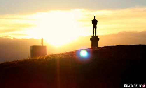 Silhouette of statue against cloudy sky during sunset