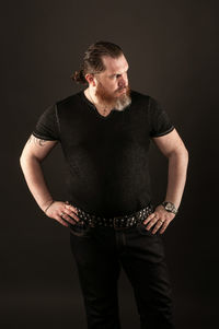 Young man standing against black background