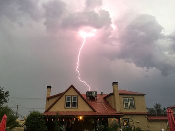 Panoramic view of lightning over house against sky