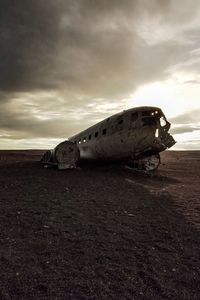 Abandoned airplane on sand against sky