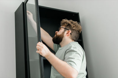 Side view of man looking through window