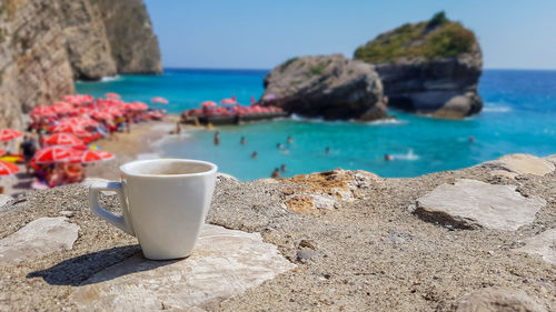 Cup of coffee on background of beautiful sea landscape with picturesque clear azure blue sea, beach 
