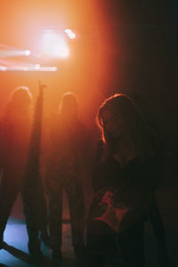 Young woman dancing in dark with red spotlight at nightclub