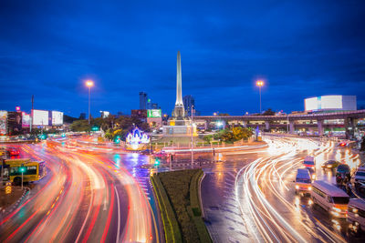 Light trails on road in city against sky at night