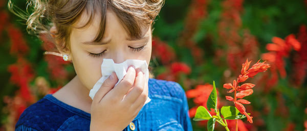 Close-up of girl wiping nose with tissue