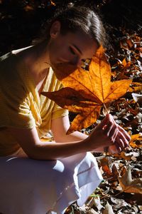 Woman sitting on maple leaves during autumn