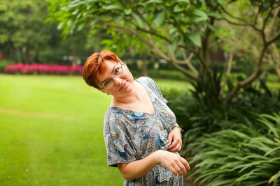 Portrait of a smiling young woman standing against plants