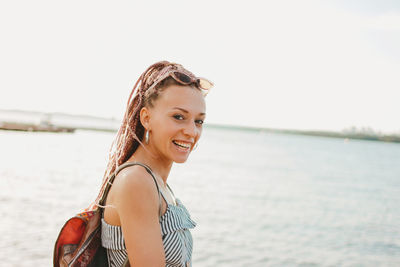 Portrait of happy young woman standing by lake
