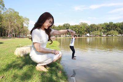 Optical illusion of smiling mid adult woman holding man over lake