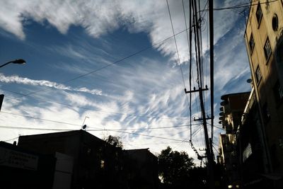 Low angle view of electricity pylon against cloudy sky