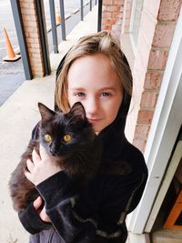 Portrait of young girl with black cat at home