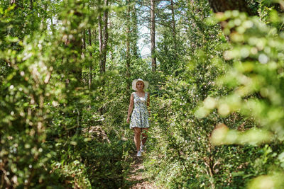 Girl standing by tree in forest