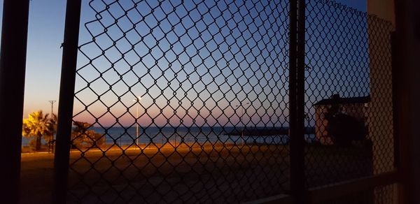 Chainlink fence against sky during sunset