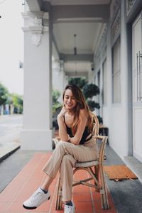 Young woman sitting on chair in corridor