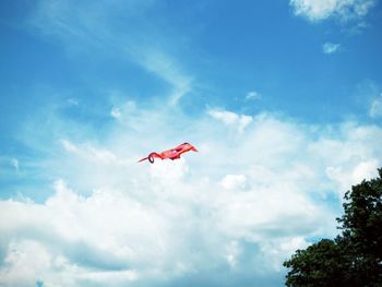 Low angle view of kite flying in mid-air against cloudy sky