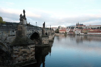 Arch bridge over river against buildings in city