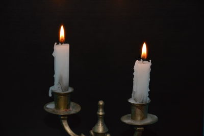 Close-up of burning candle against black background