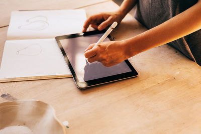 Midsection of woman using smart phone on table