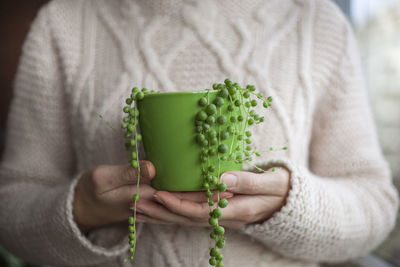 Midsection of woman holding plant buds in container