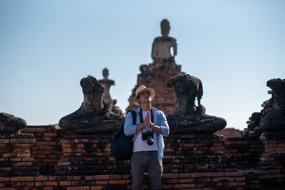 Man standing at historic temple against sky