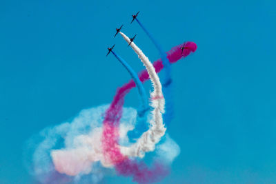 Low angle view of airplanes flying against blue sky