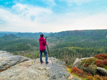 Female tourist with camera on tripod taking travel picture mountain peak. natural landscape