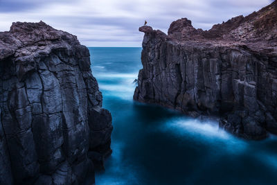 Rock formations by sea against sky