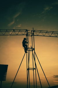 Silhouette man working on metal structure during sunset
