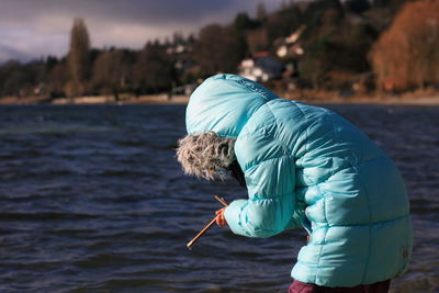 Person in turquoise cloth by lake