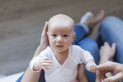 Low section woman holding cute baby girl sitting on floor at home